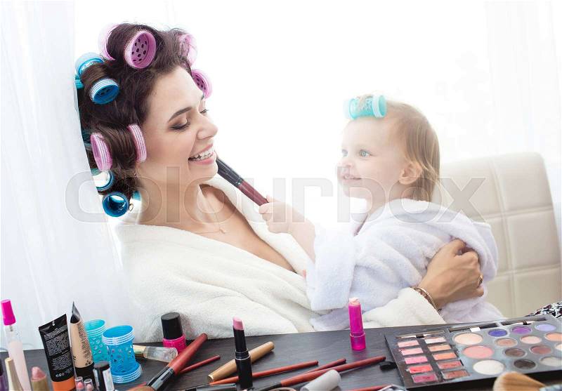 Happy family. Mother and daughter are doing hair, manicures, makeup and having fun. Mother and daughter sitting at dressing table at house, stock photo