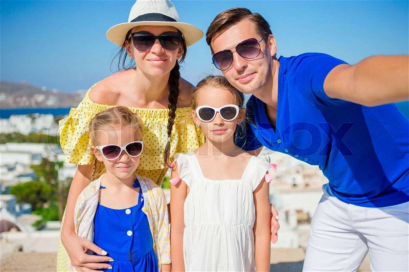 Family vacation in Europe. Parents and kids taking selfie background Mykonos town in Greece, stock photo