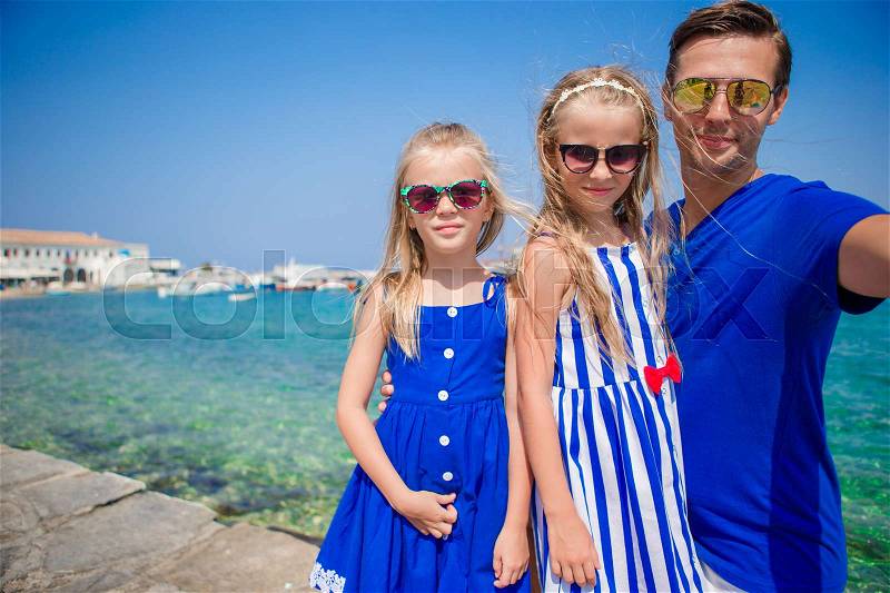 Family vacation in Europe. Father and kids taking selfie background Mykonos town in Greece, stock photo