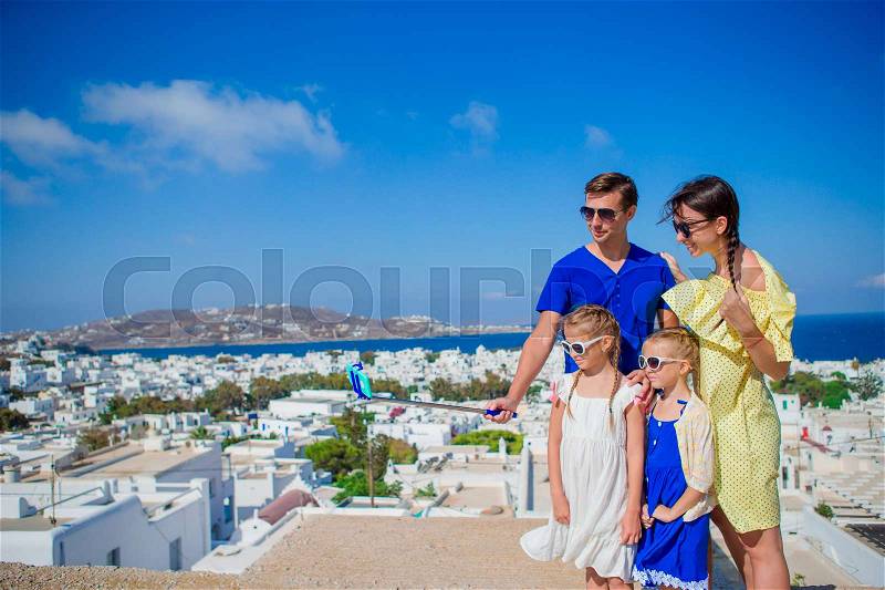 Family vacation in Europe. Parents and kids taking selfie photo background Mykonos town in Greece, stock photo