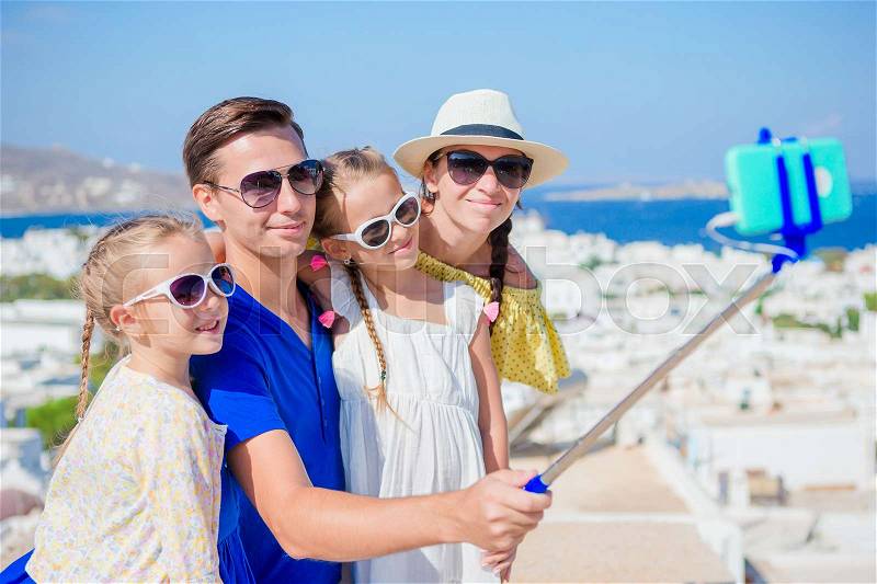Family vacation in Europe. Parents and kids taking selfie photo background Mykonos town in Greece, stock photo
