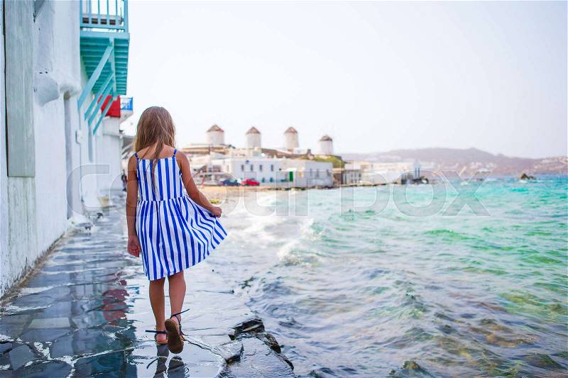 Adorable little girl at Little Venice the most popular tourist area on Mykonos island, Greece. Beautiful kid smile and look in the camera on Little Venice background, stock photo