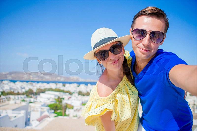 Selfie couple taking pictures at Mykonos island, Cyclades. Tourists people taking travel photos with smartphone on summer holidays, stock photo