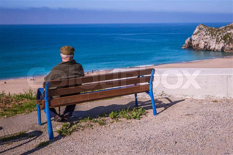Older man sitting on a bench by the seaside and thinking about life, stock photo
