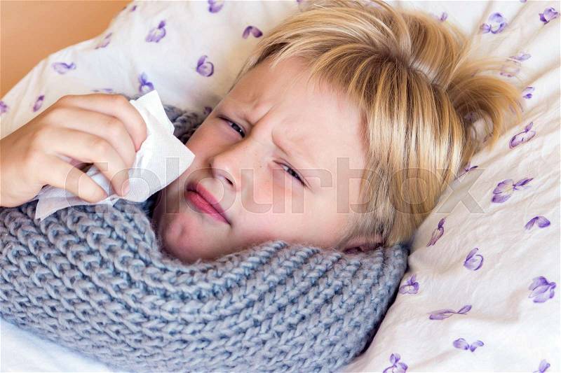 Sick little child boy blowing nose laying in bed with sad face - healthcare and medicine concept, stock photo
