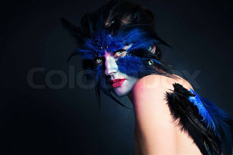 Halloween Makeup. Fantasy Bird Woman with Artistic Make-up on Blue Background and Copy space for Text, stock photo