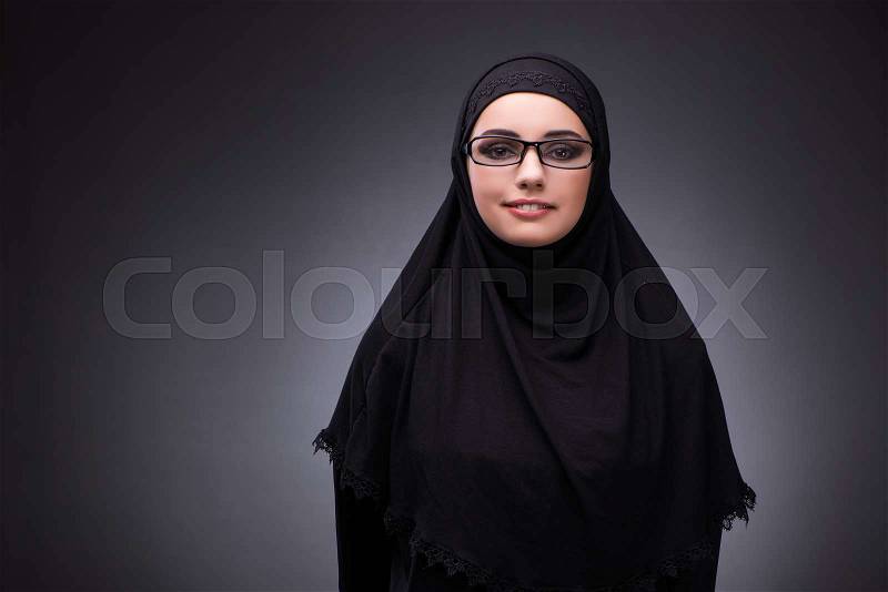 Muslim woman in black dress against dark background, stock photo