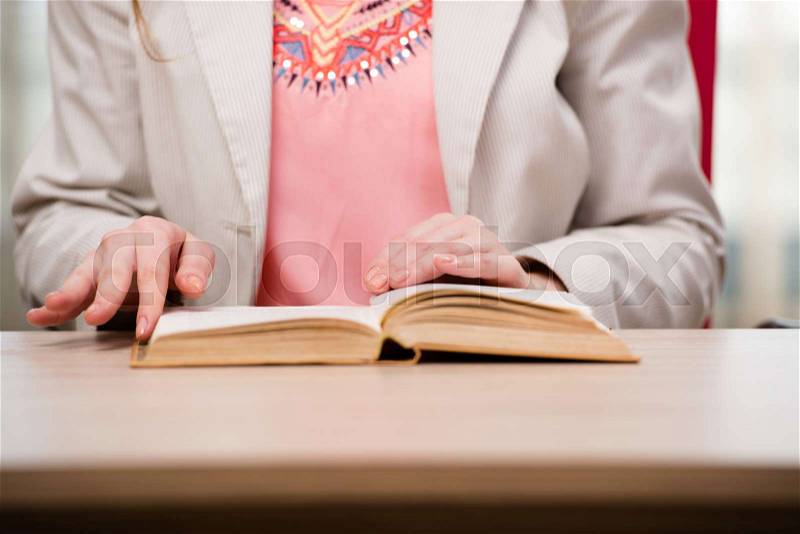 Young student reading book in preparation for exams, stock photo