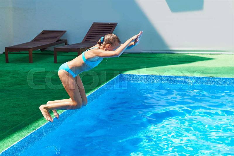 Girl jumping into a resort pool, stock photo