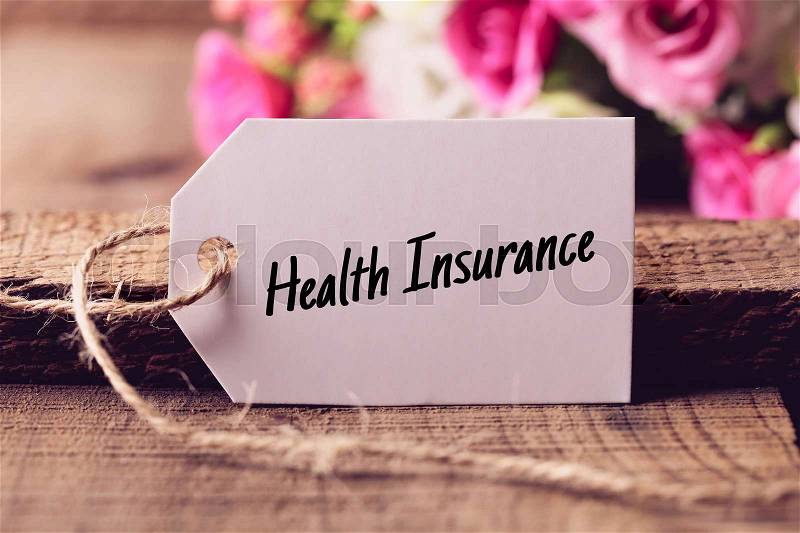 Text Health Insurance written on white label with nice blurred flower background, stock photo