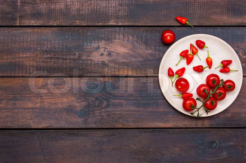 The cherry tomatoes, peppers, chilli on wooden table, top view, stock photo