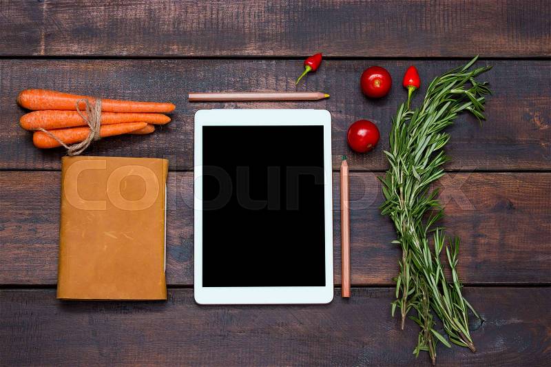The tablet, notebook, fresh bitter and sweet pepper on wooden table background, stock photo