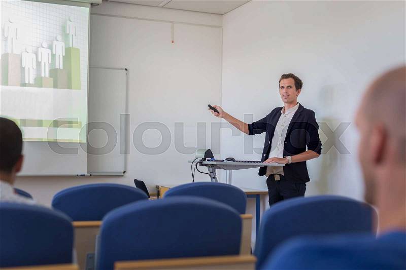 Relaxed confident smart student presenting his study work in front of whiteboard, defending his thesis. Doctoral thesis defense on faculty, stock photo