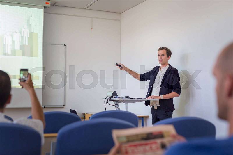 Relaxed confident smart student presenting his study work in front of whiteboard, defending his thesis. Doctoral thesis defense on faculty, stock photo