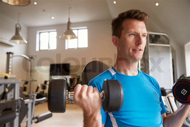 Man practicing bicep curls with dumbbells at a gym, close up, stock photo