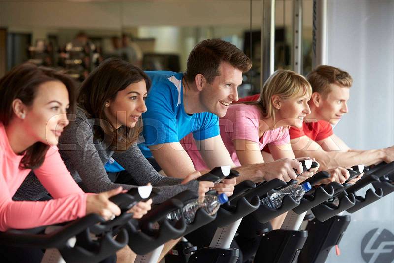 Side view of a spinning class on exercise bikes at a gym, stock photo
