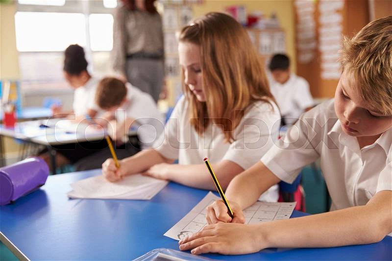 Boy and girl working in primary school class, close up, stock photo