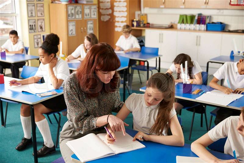 Teacher helping a girl with work at her desk, elevated view, stock photo