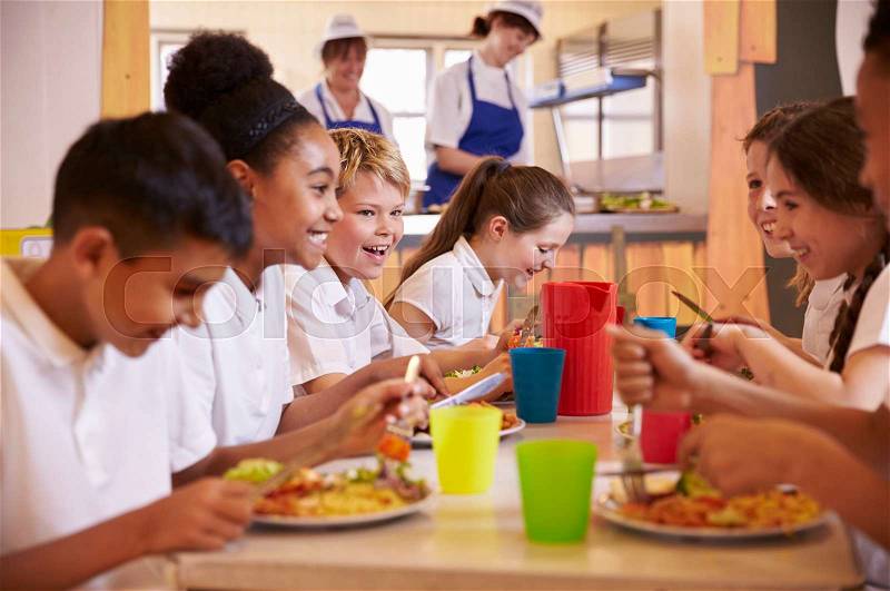 Primary school kids at a table in school cafeteria, close up, stock photo