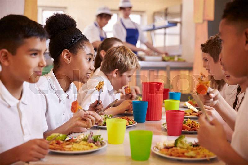 Primary school kids eat lunch in school cafeteria, close up, stock photo