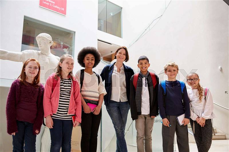 Portrait Of Teacher With Class Standing Inside Museum, stock photo