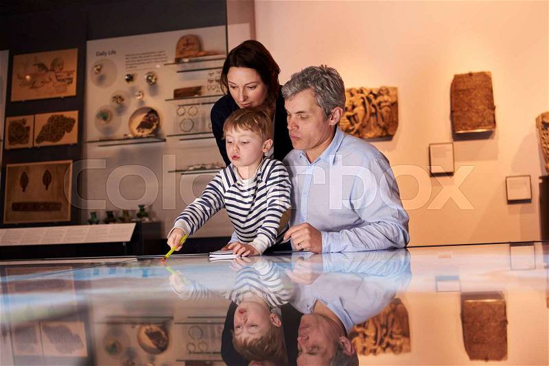 Family On Trip To Museum Looking At Map Together, stock photo
