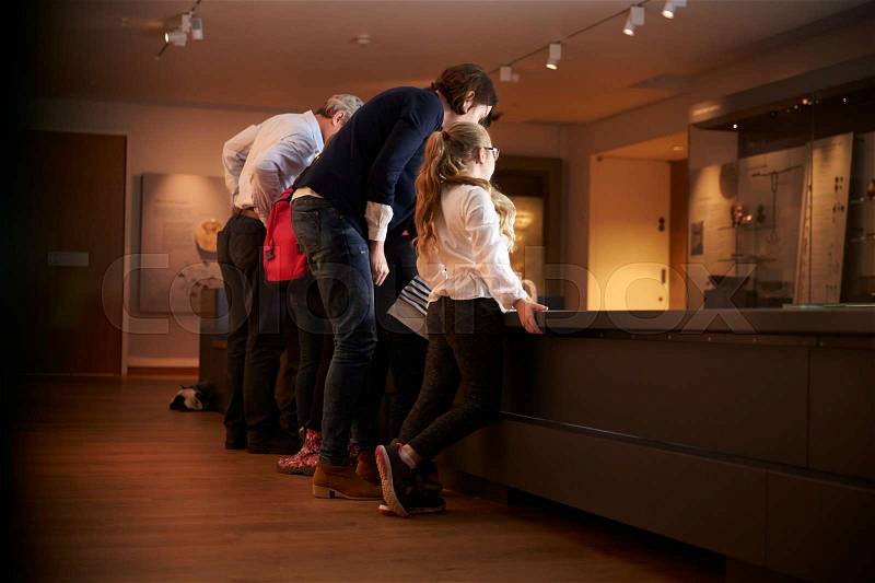 Rear View Of Pupils On School Trip To Museum Looking At Map, stock photo
