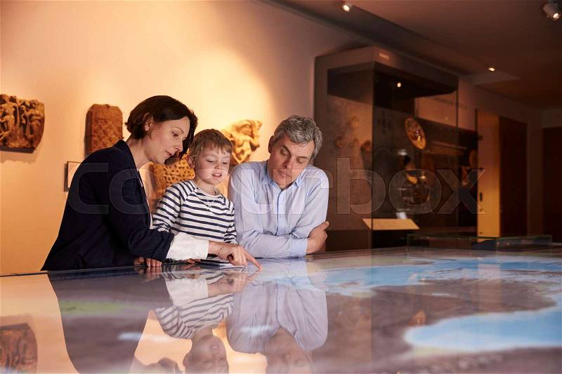 Family On Trip To Museum Looking At Map Together, stock photo