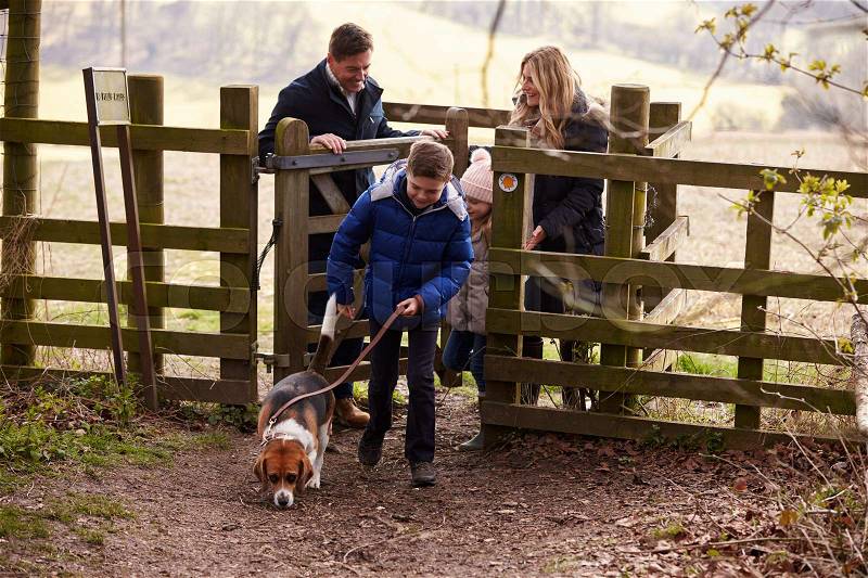 Family with a dog passing through a gate in the countryside, stock photo