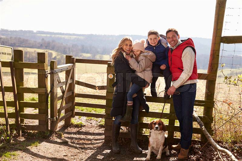 Happy family with dog by a gate in the countryside, stock photo