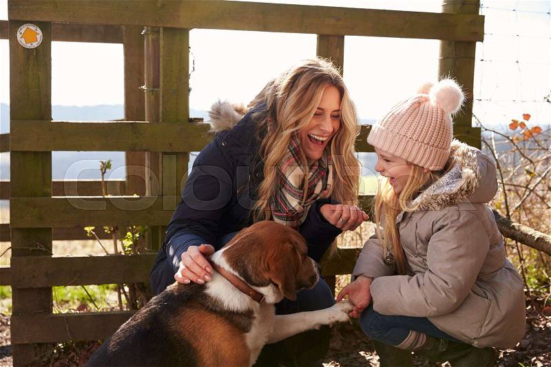 Mother and daughter play with dog in countryside, close up, stock photo