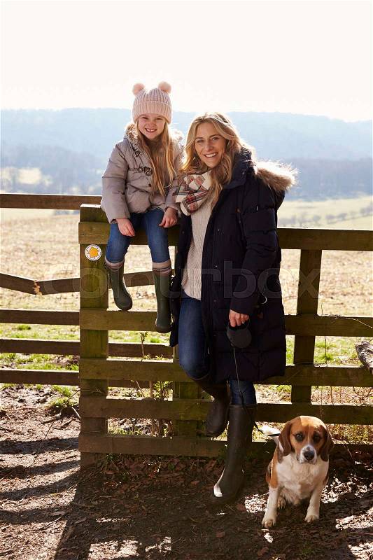 Mother and daughter by a country gate with pet dog, vertical, stock photo