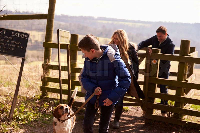 Boy looks down at pet dog during family walk in countryside, stock photo