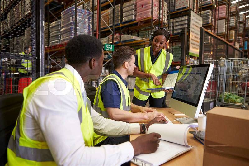 Team discussing warehouse logistics in an on-site office, stock photo