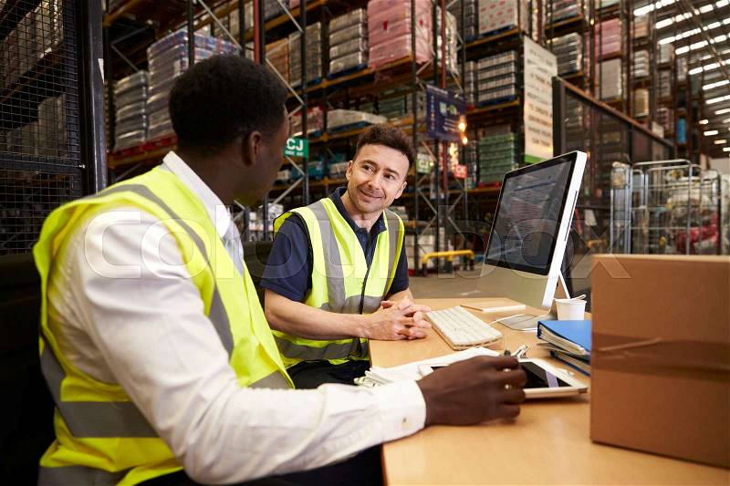 Staff discuss warehouse logistics in an on-site office, stock photo