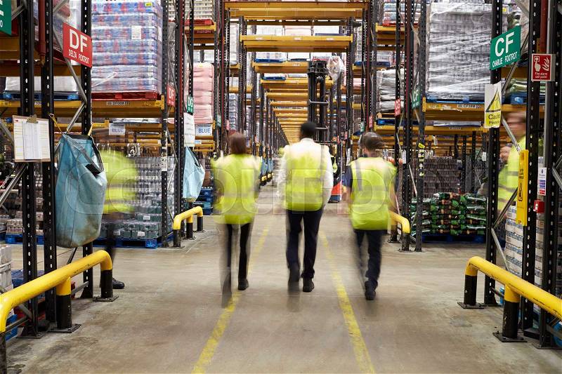 Staff in reflective vests walking from camera in a warehouse, stock photo