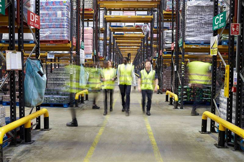 Staff in reflective vests walking to camera in a warehouse, stock photo