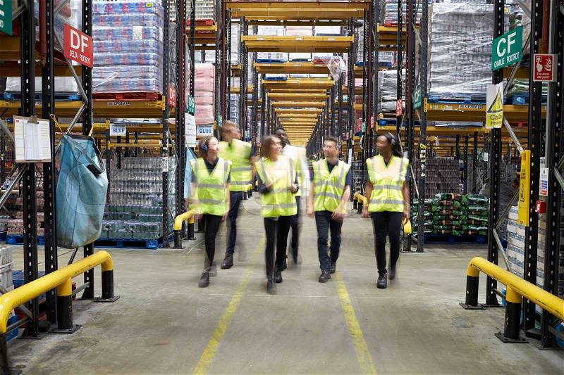 Staff in reflective vests walking to camera in a warehouse, stock photo