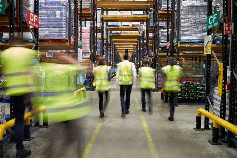 Staff in reflective vests walking in a warehouse, back view, stock photo