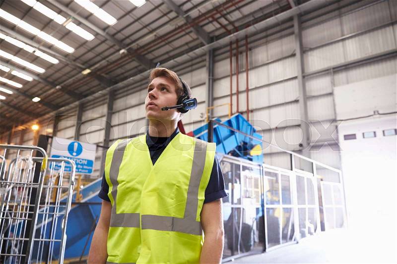 Man with reflective vest and headset standing in a warehouse, stock photo