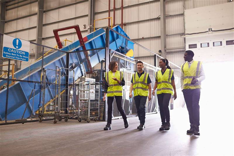 Staff wearing reflective vests in an industrial interior, stock photo