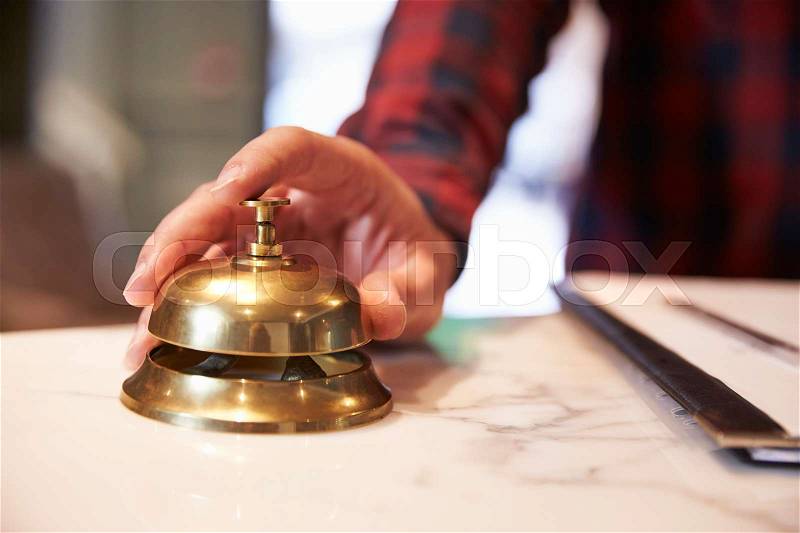 Close Up Of Guest\'s Hand On Hotel Reception Bell, stock photo