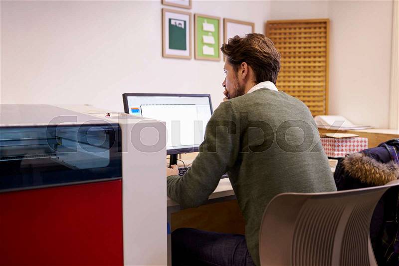Male Designer Operating CAD System For Laser Cutter, stock photo