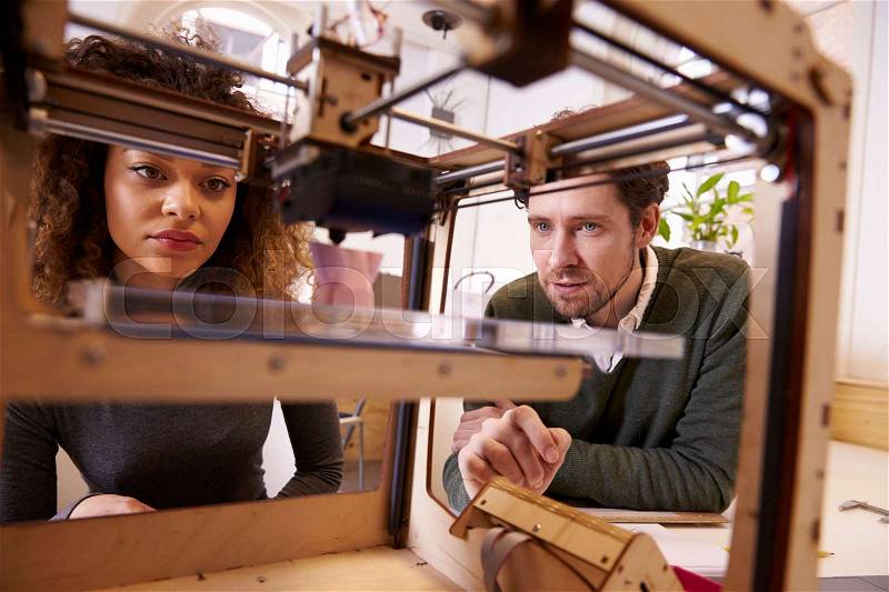 Two Designers Working With 3D Printer In Design Studio, stock photo