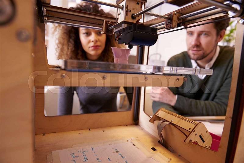 Two Designers Working With 3D Printer In Design Studio, stock photo