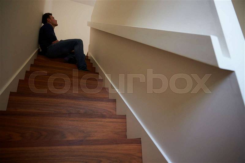 Depressed Young Man Sitting On Stairs At Home, stock photo