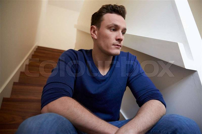 Depressed Young Man Sitting On Stairs At Home, stock photo