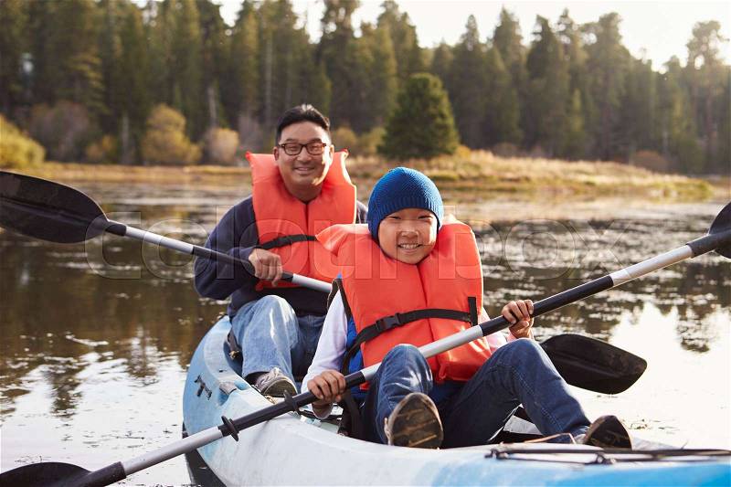 Father and son kayaking on a rural lake, front view, stock photo
