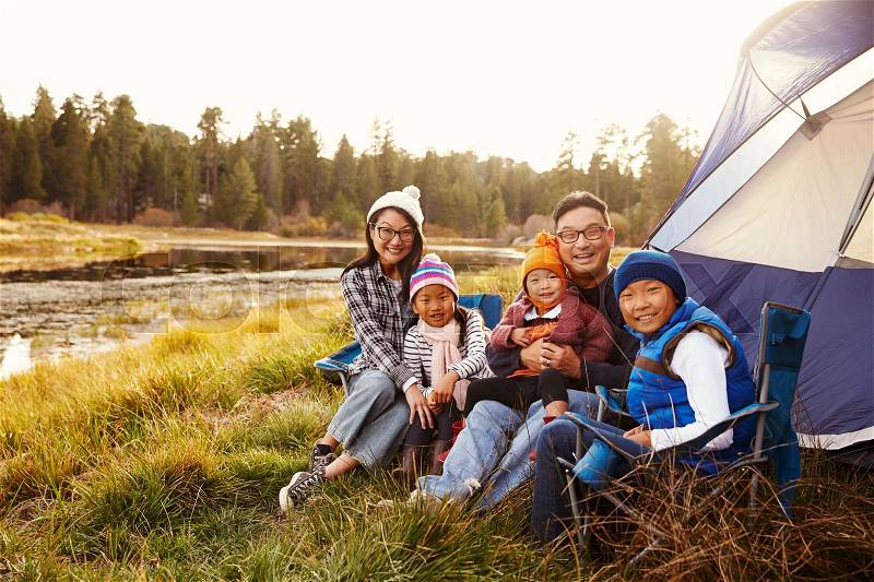 Asian family sitting outside their tent, looking to camera, stock photo