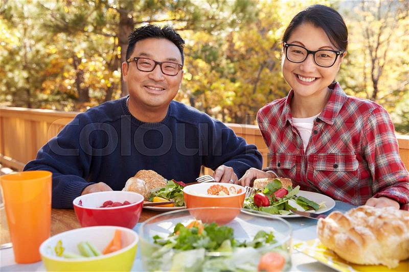 Asian couple eating outside at a table look to camera, stock photo
